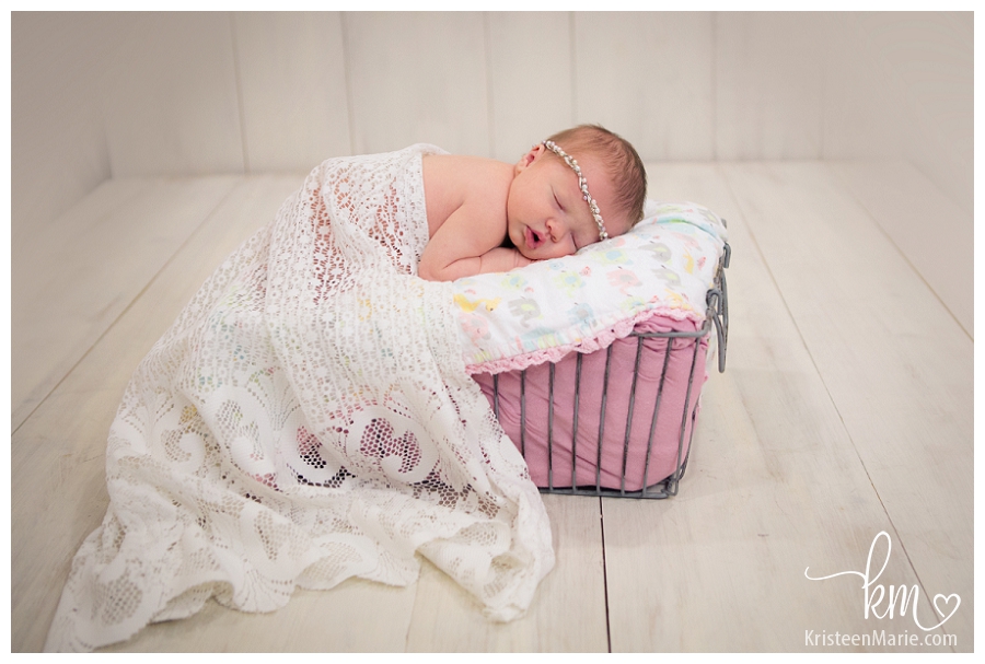 baby in a basket with lace and pink frill