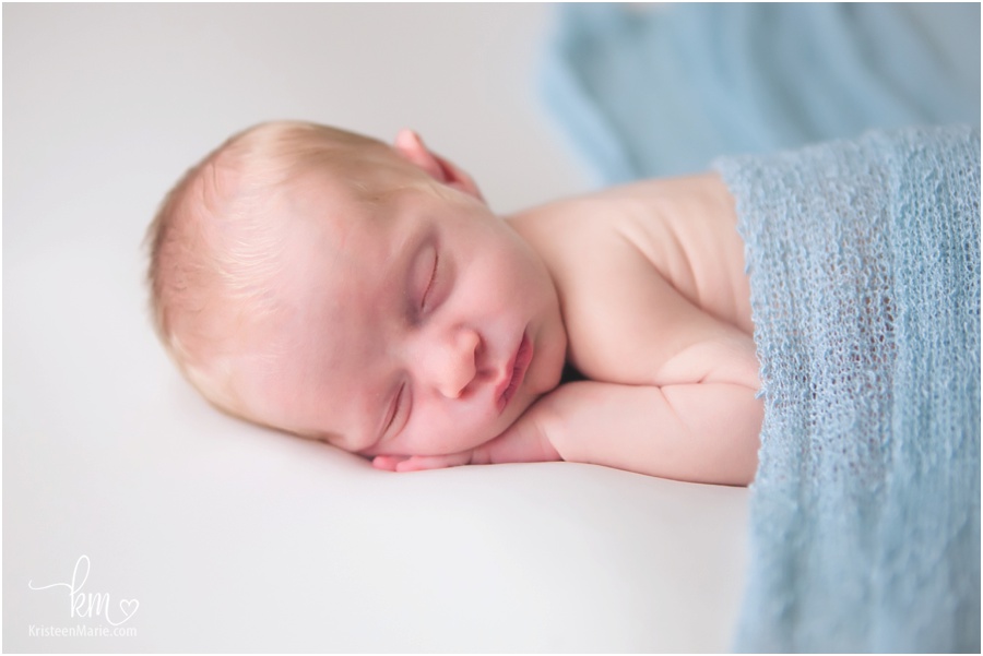 sleeping newborn boy with blue wrap