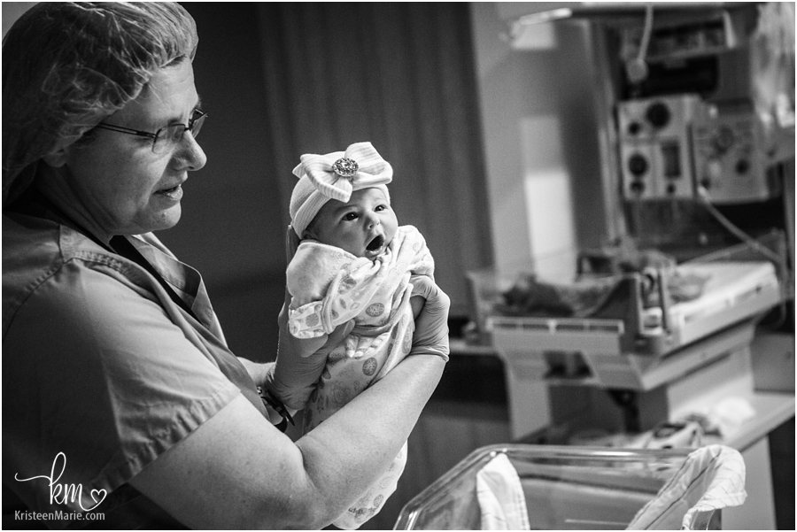 nurse holding up newborn baby