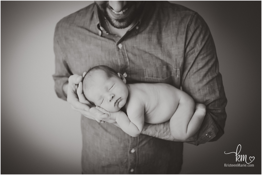 newborn baby in dad's hands - black and white image