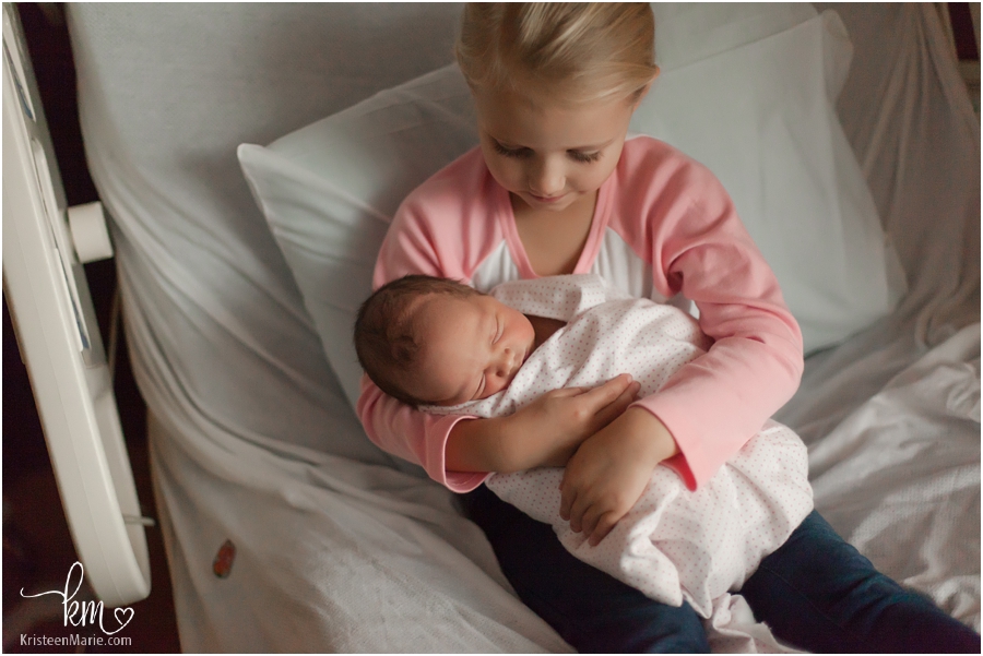 big sister holding newborn baby sister