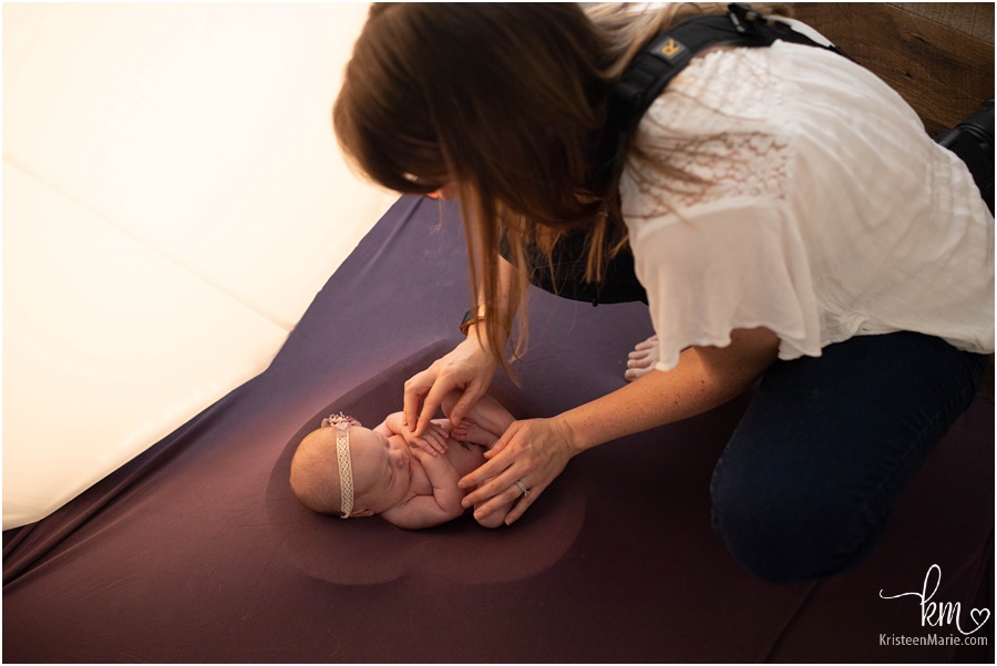 photographer working with newborn baby in heart prop