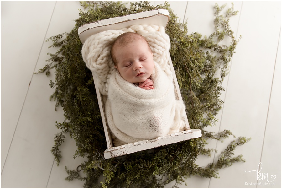sleeping newborn boy with greenery