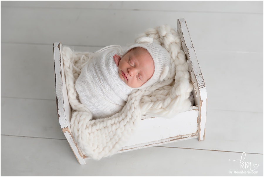 sleeping newborn boy in wood crib prop