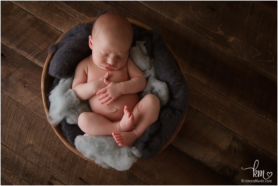 moddly newborn picture of baby in bowl on dark wood and blue fluff