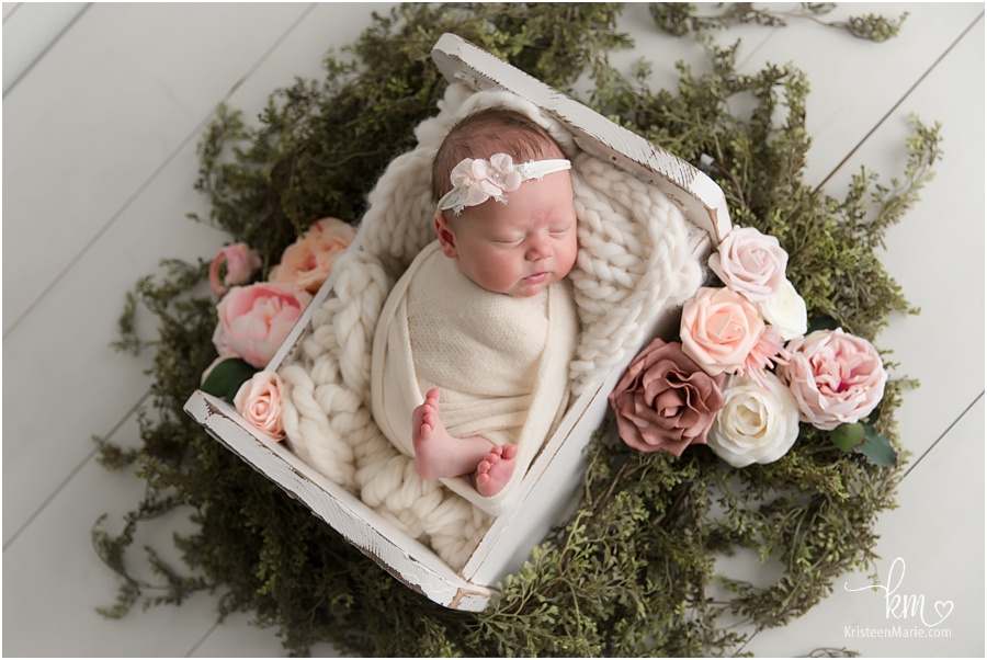 newborn baby girl with blush and pink flowers and greenery