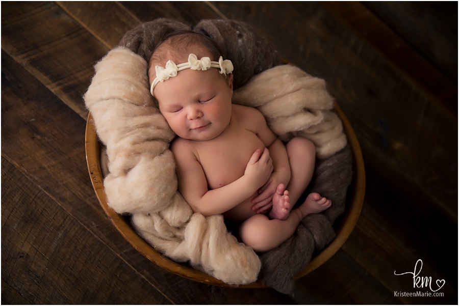 newborn baby girl in bowl and bow in hair