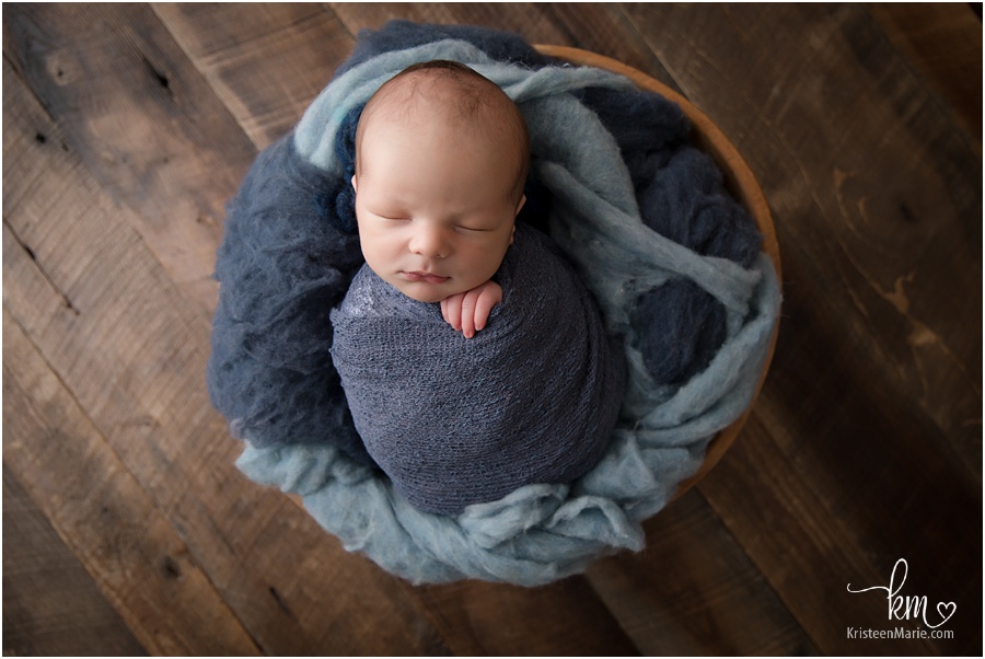 newborn baby boy in bowl wrapped in blue