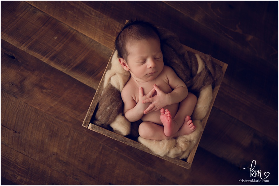 sleeping newborn boy on dark wood in box