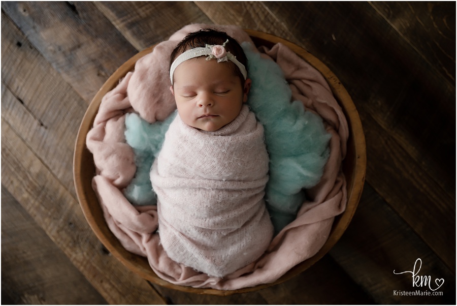 sleeping newborn girl in bowl on rustic wood