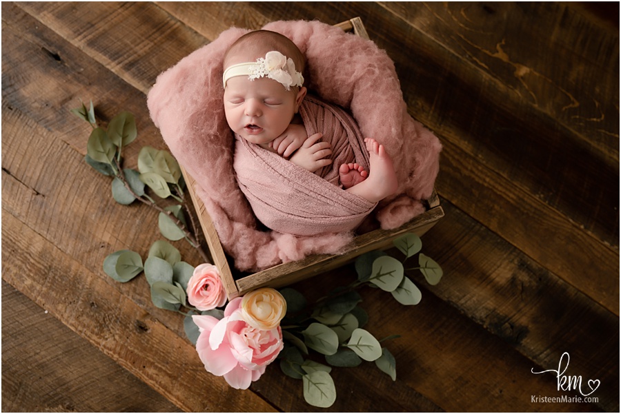 rustic newborn baby in a box with pink flowers