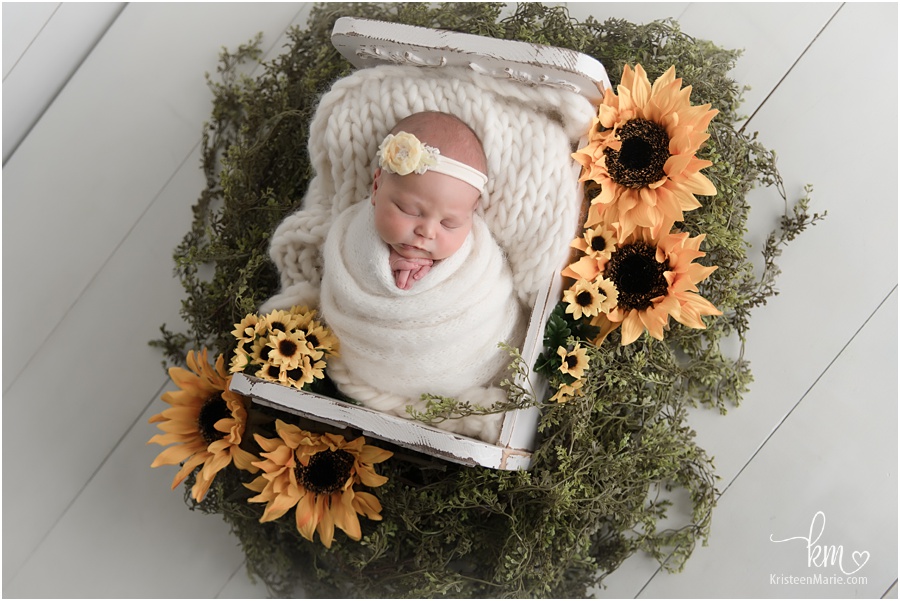 baby girl in box with sunflowers