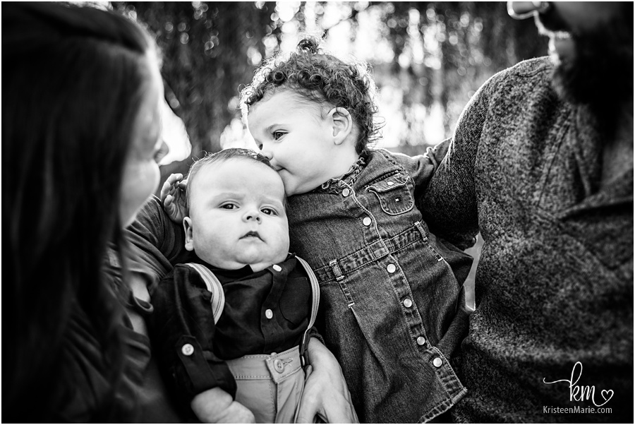black and white family image - siblings kissing