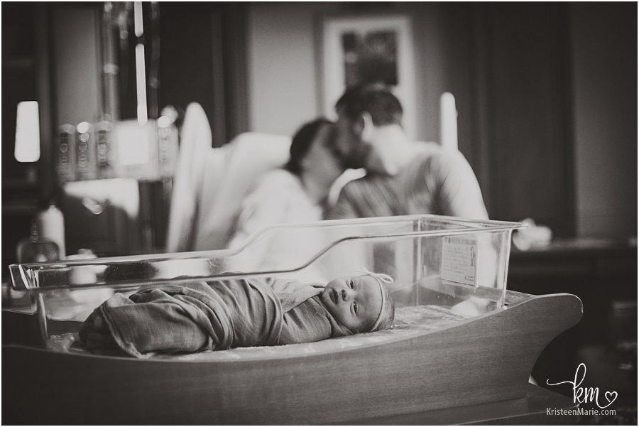black and white image of baby in hospital with parents