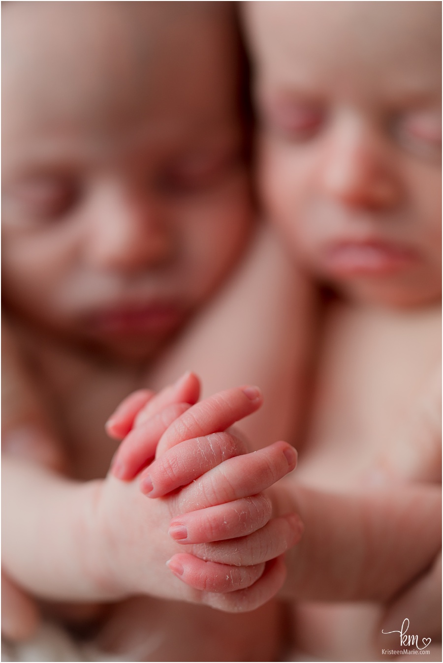 newborn twins holding hands 