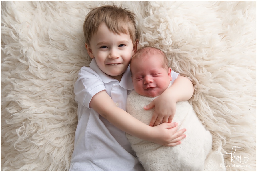 big brother holding newborn baby boy