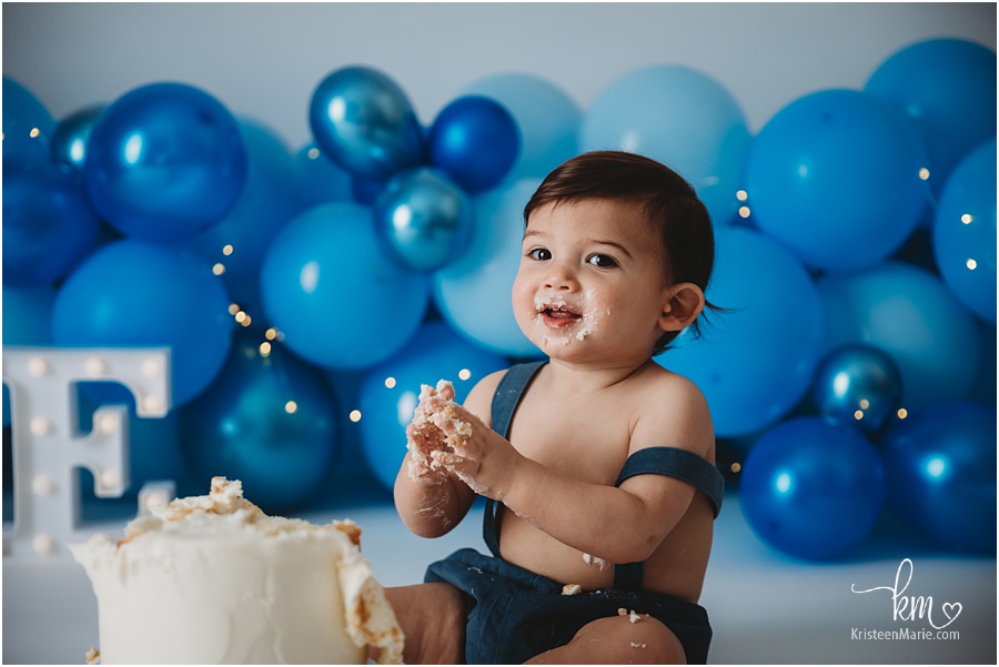 smiling and clapping baby in front of cake