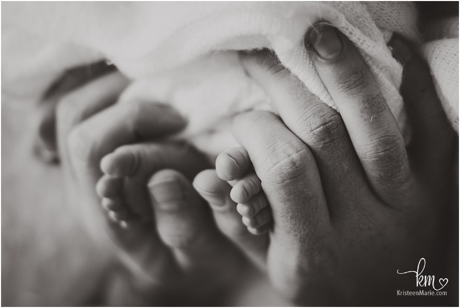 baby's feet with dad's hand in black and white