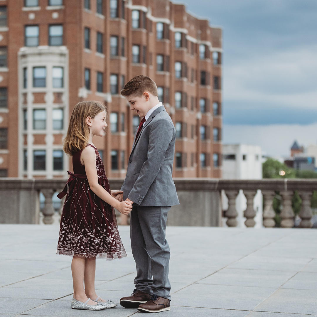 siblings holding hands with Indianapolis skyline as the backdrop