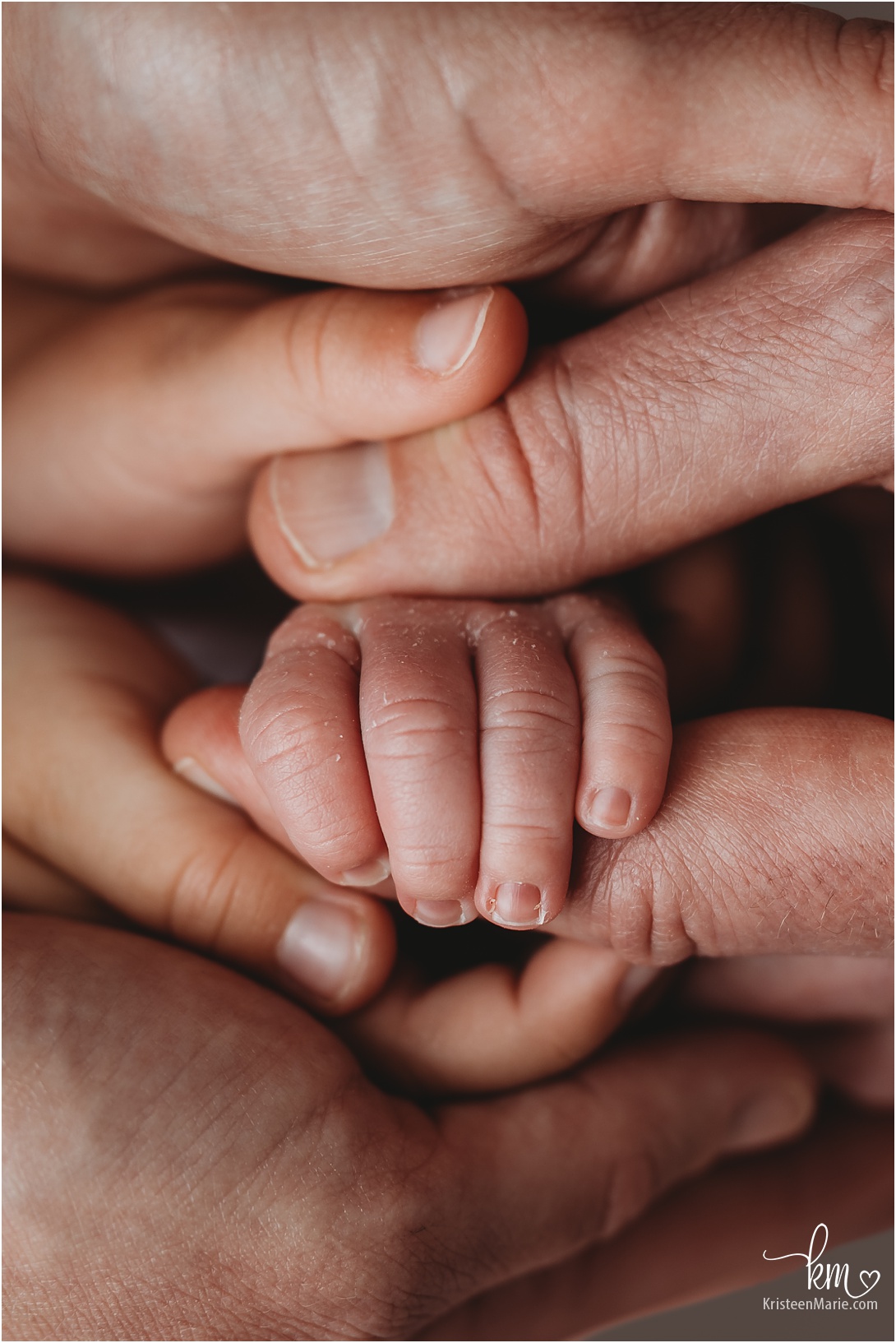 newborn baby hand surround by fingers