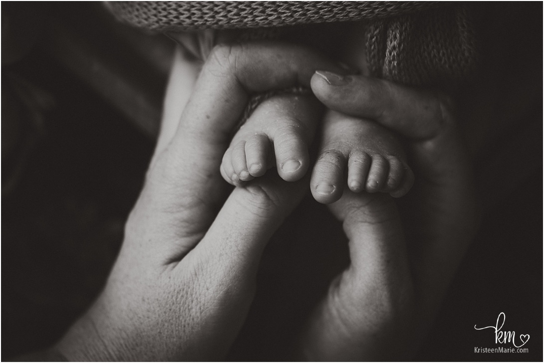 newborn baby feet with dad's hands in black and white