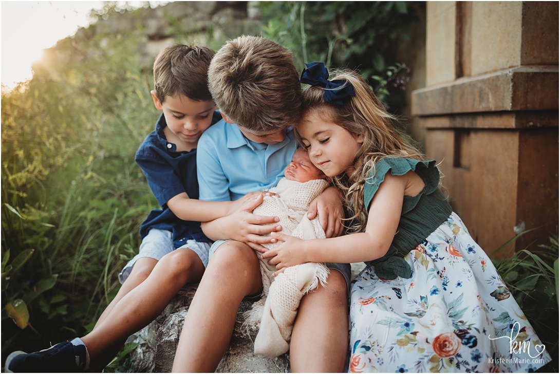 siblings with newborn baby during outdoor newborn photography session in Indianapolis, IN