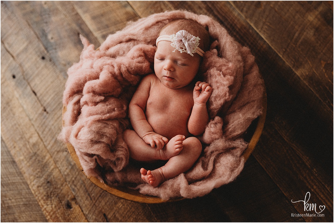 newborn girl in pink on dark rustic wood