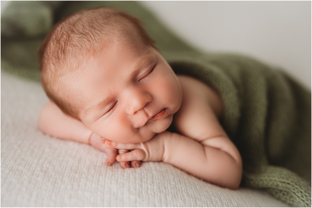 sleeping newborn boy with green wrap