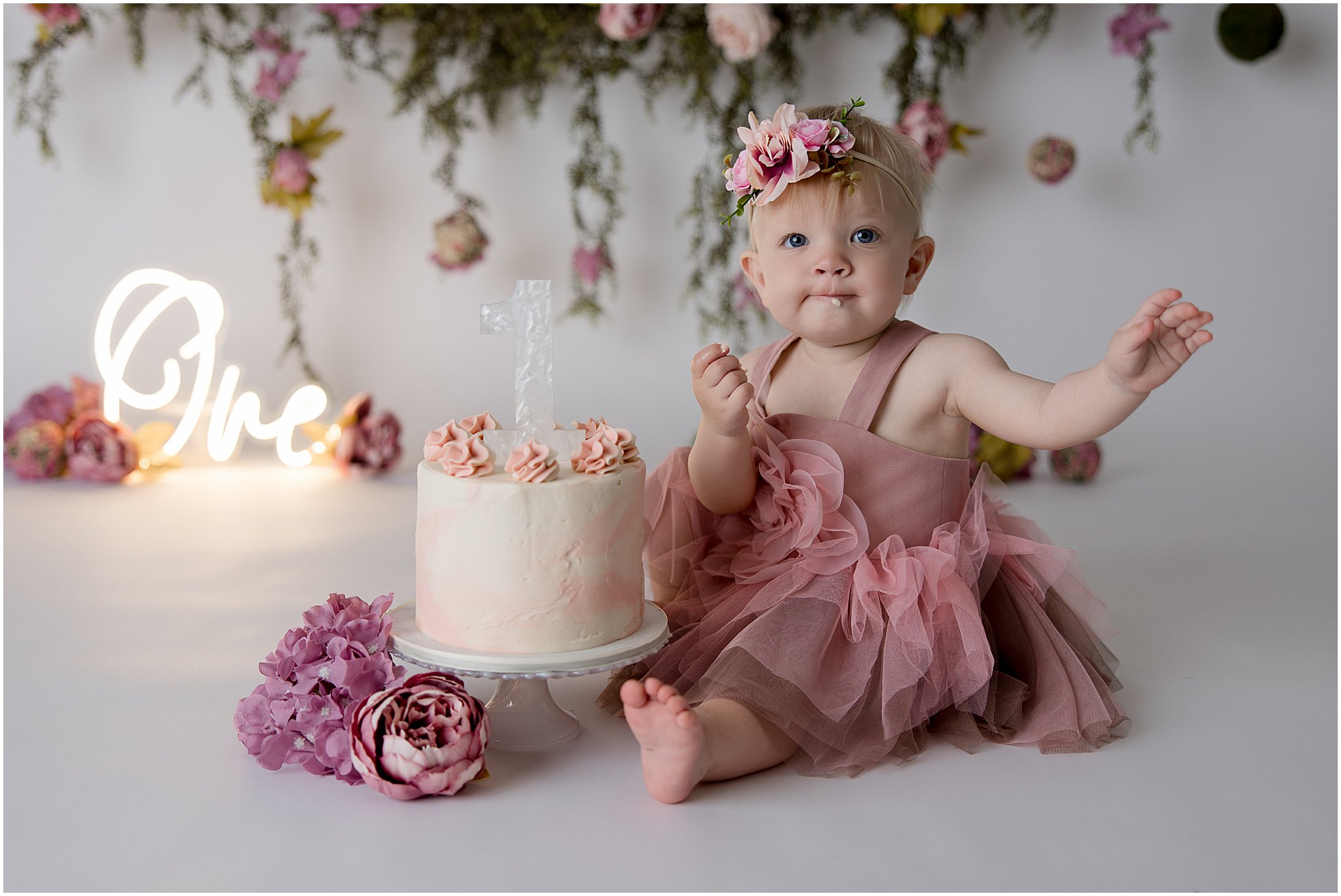Smiling baby in tutu dress celebrating first birthday cake smash in Zionsville