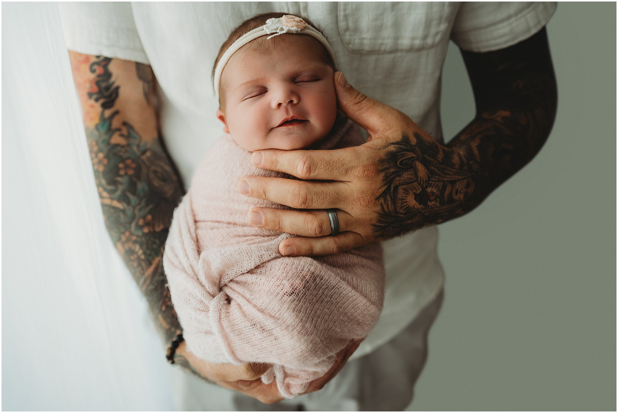 Dad holding newborn daughter in tattooed arms during Westfield photography session