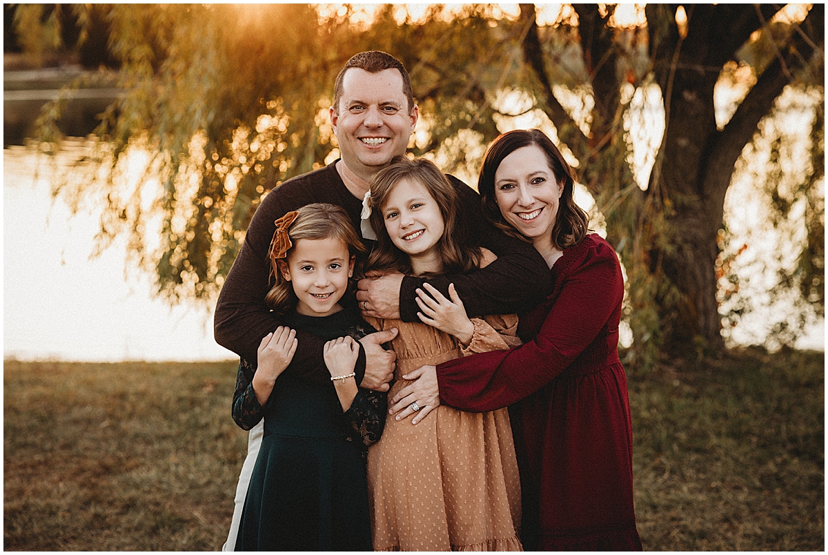 Carmel Indiana family photographer captures parents cuddling kids at golden hour.