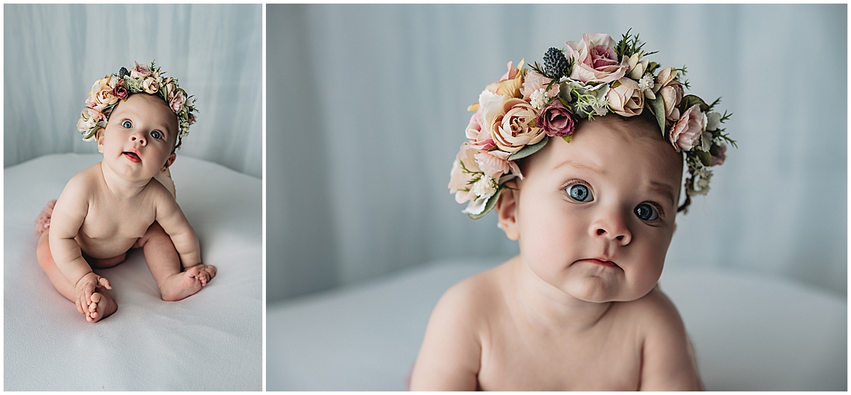 Close-up of baby girl’s big blue eyes and soft grin during sitter milestone session