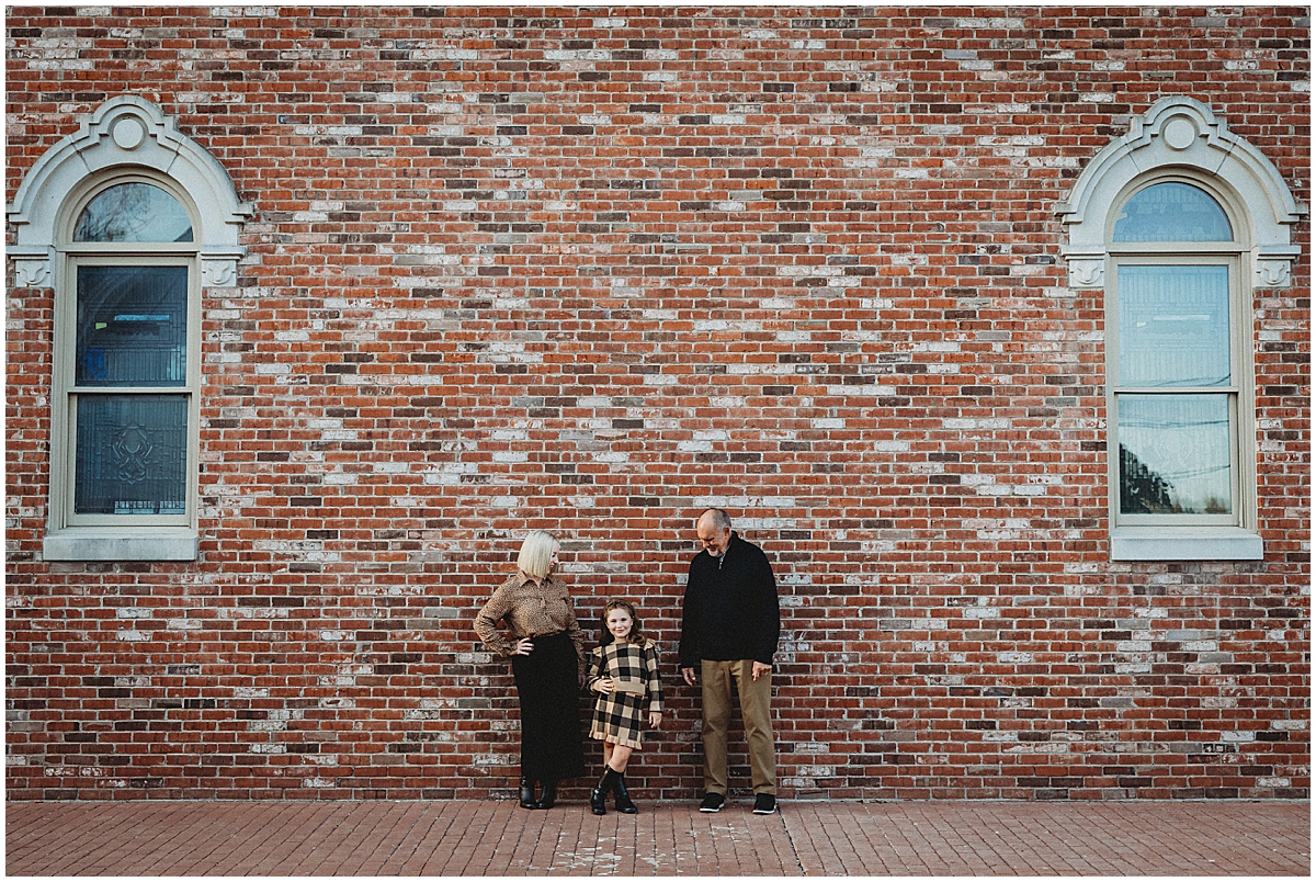 Zionsville family against brick wall in downtown Zionsville