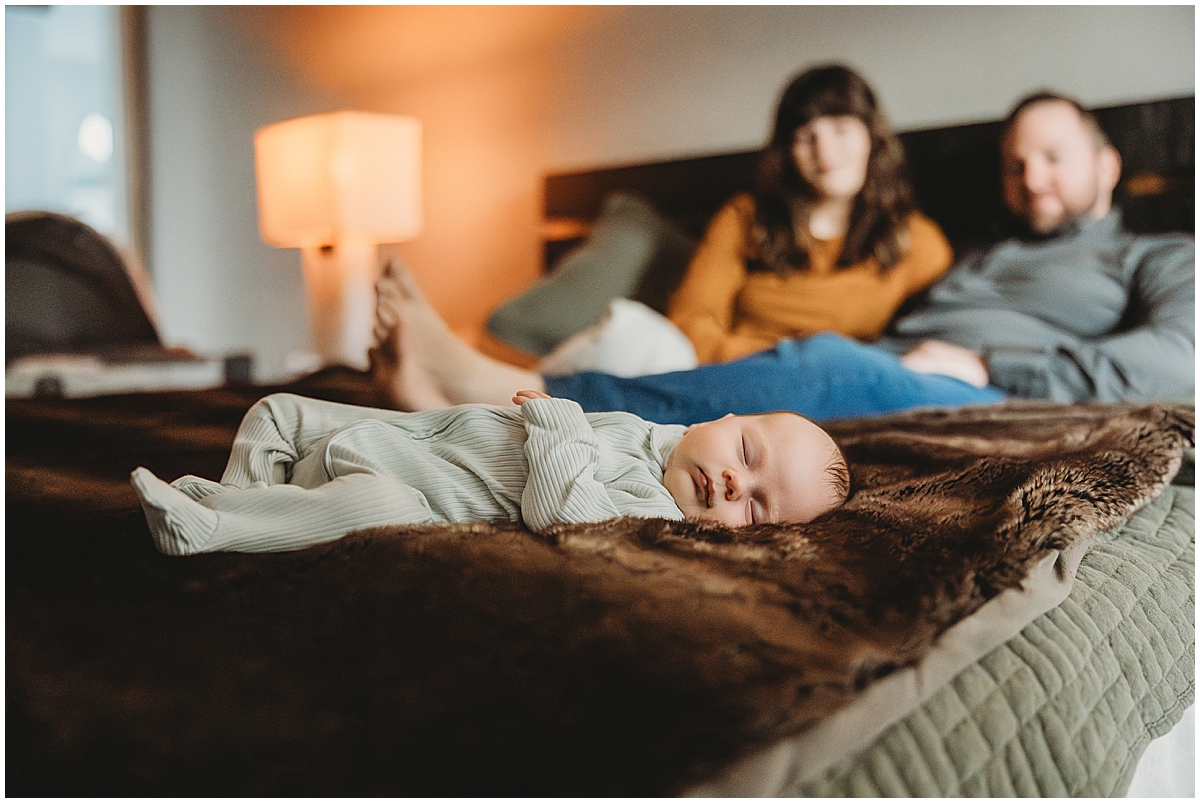 sleeping baby with mom and dad in background