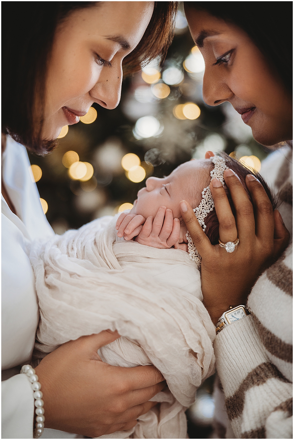 same sex couple with newborn baby girl in front of Christmas tree 