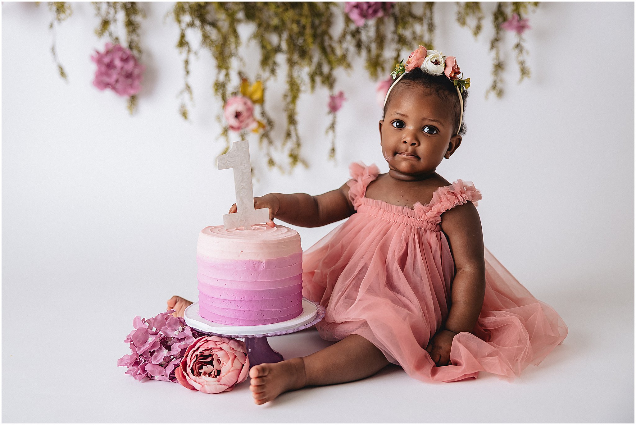 One year old baby girl sitting with pink ombre cake during Indianapolis cake smash photo session