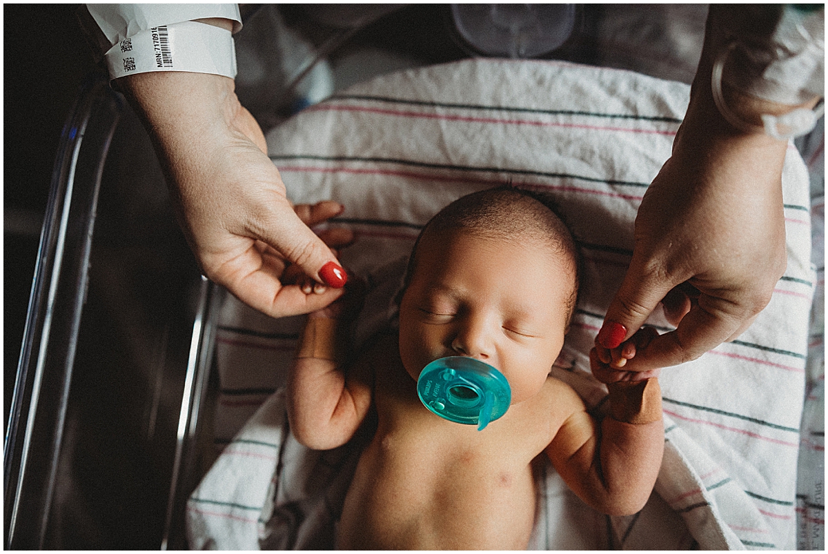 newborn holding dad's fingers in hospital