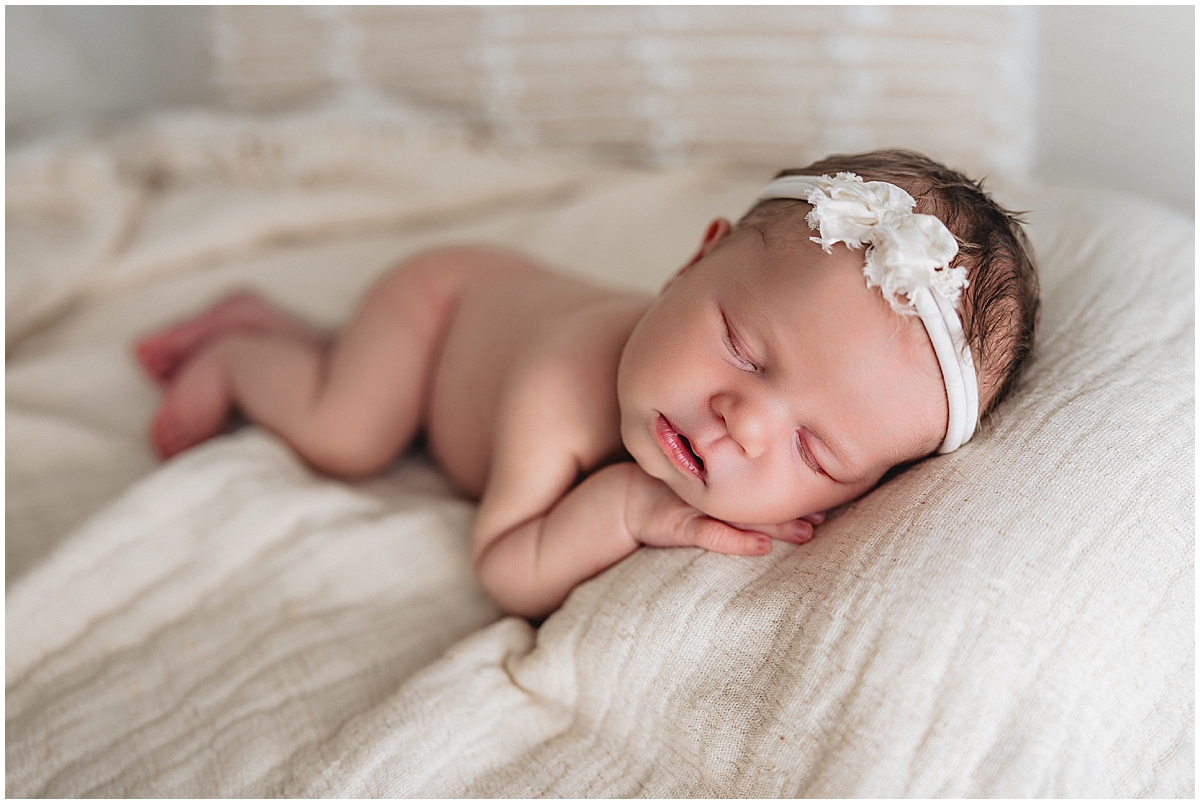 Whitestown newborn photographer capturing posed newborn baby girl sleeping on neutral fabric backdrop