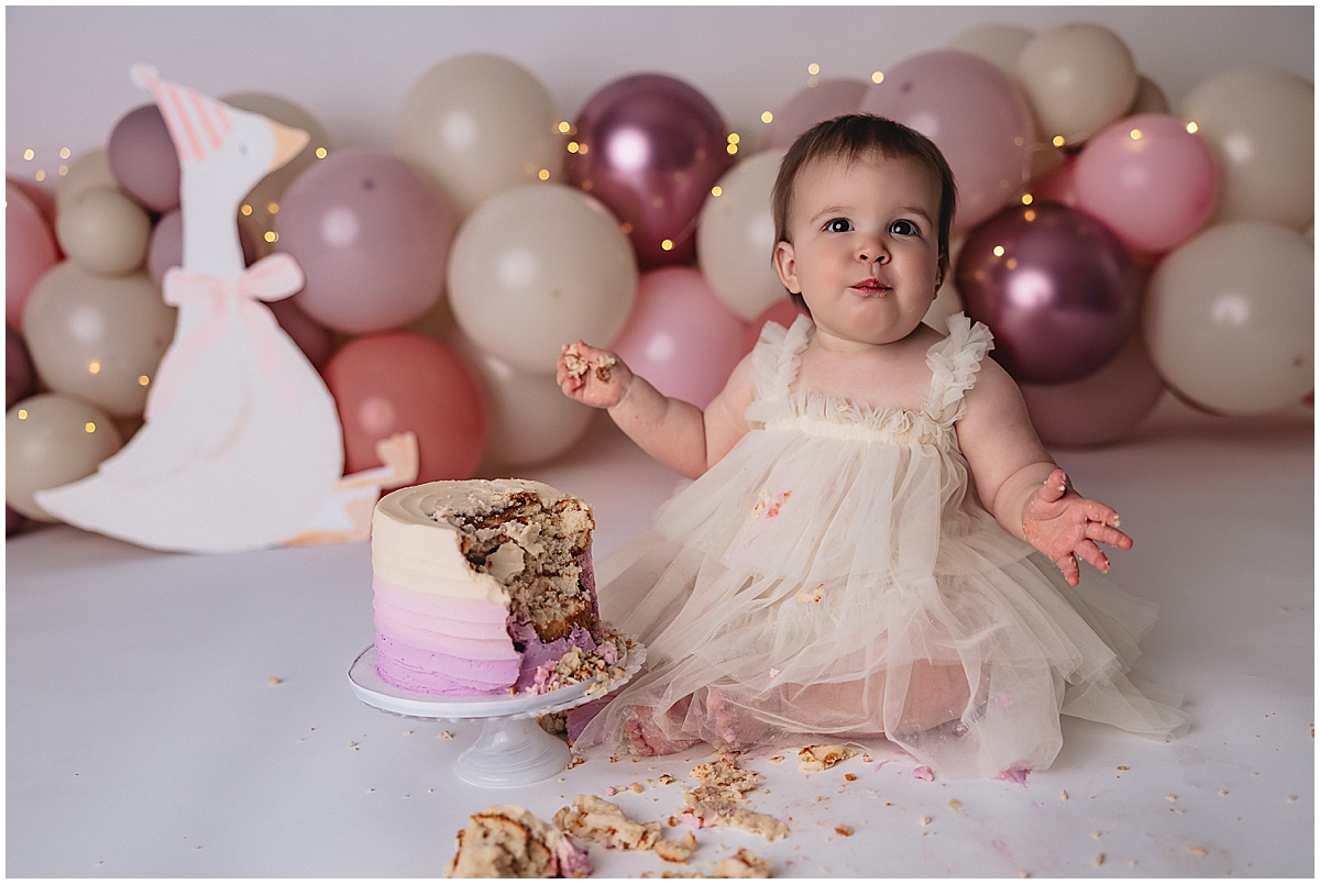 Zionsville cake smash photographer baby girl eating cake with frosting on hands and face