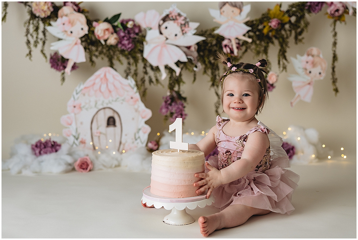 Indianapolis photographer cake smash session with baby girl in pink fairy outfit and first birthday cake