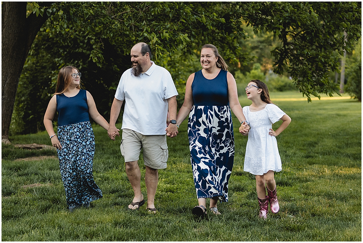 Indianapolis family photographer capturing parents and two daughters walking together during a spring mini session