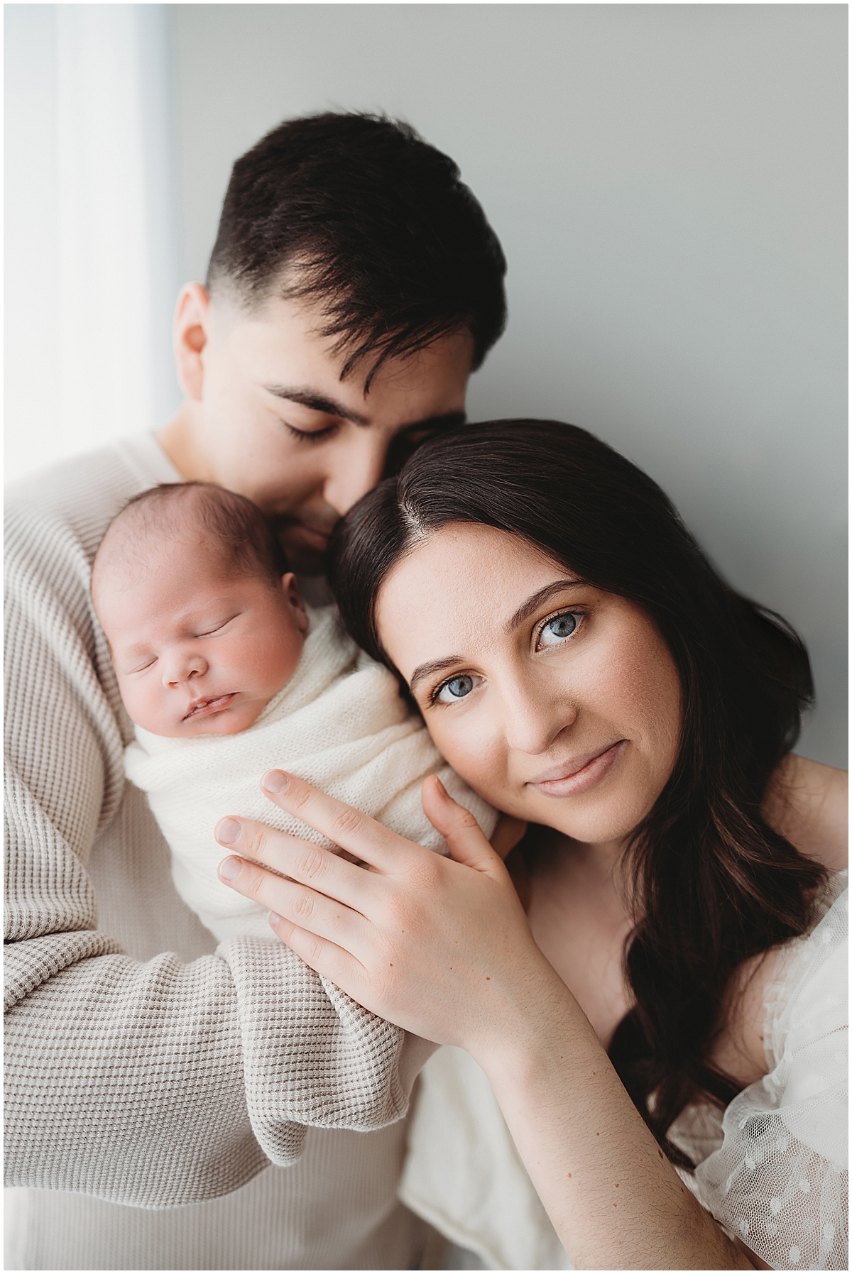 Indianapolis newborn photographer capturing soft neutral family portrait with parents holding sleeping newborn baby.