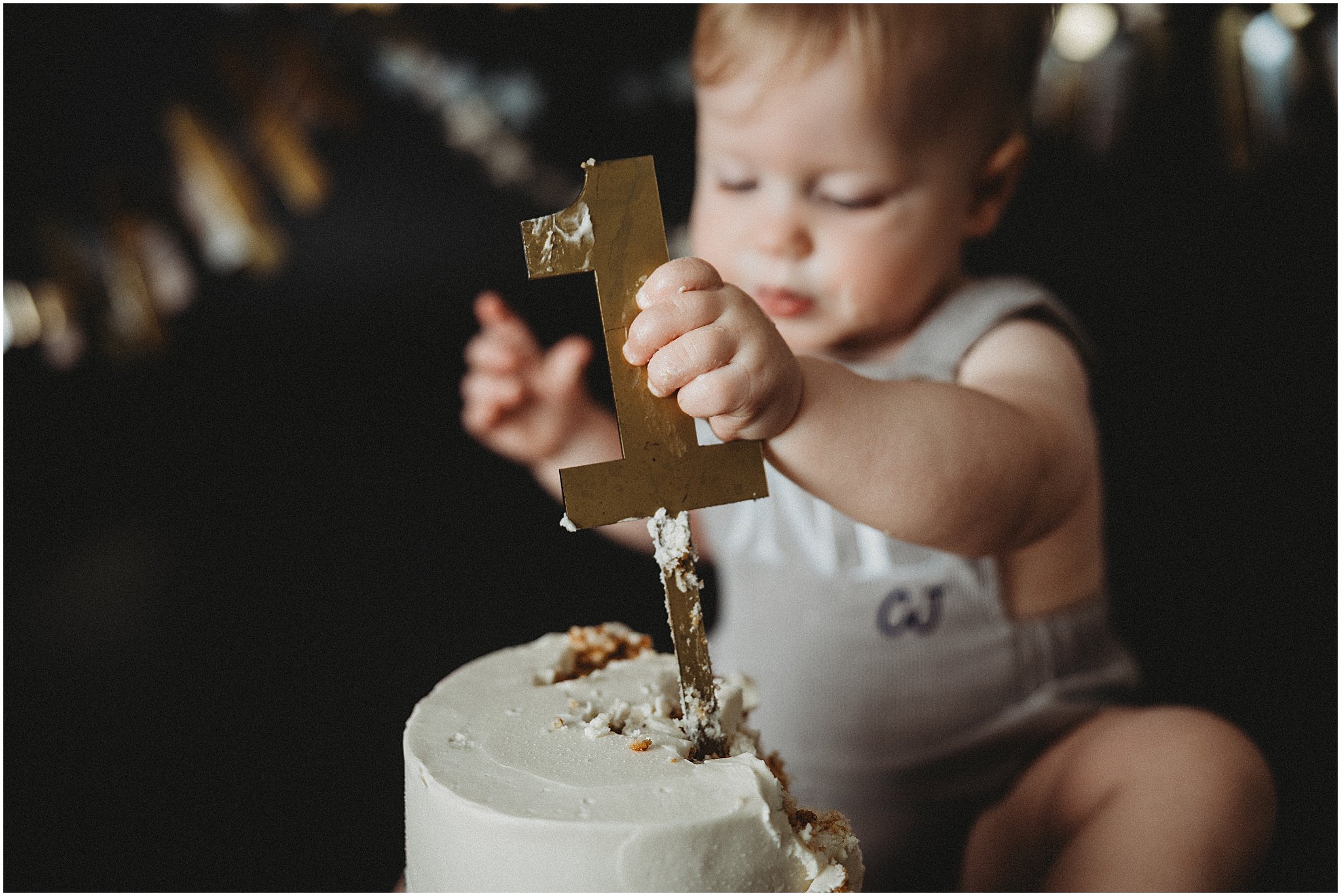 Baby boy pulling the gold number one topper out of his birthday cake