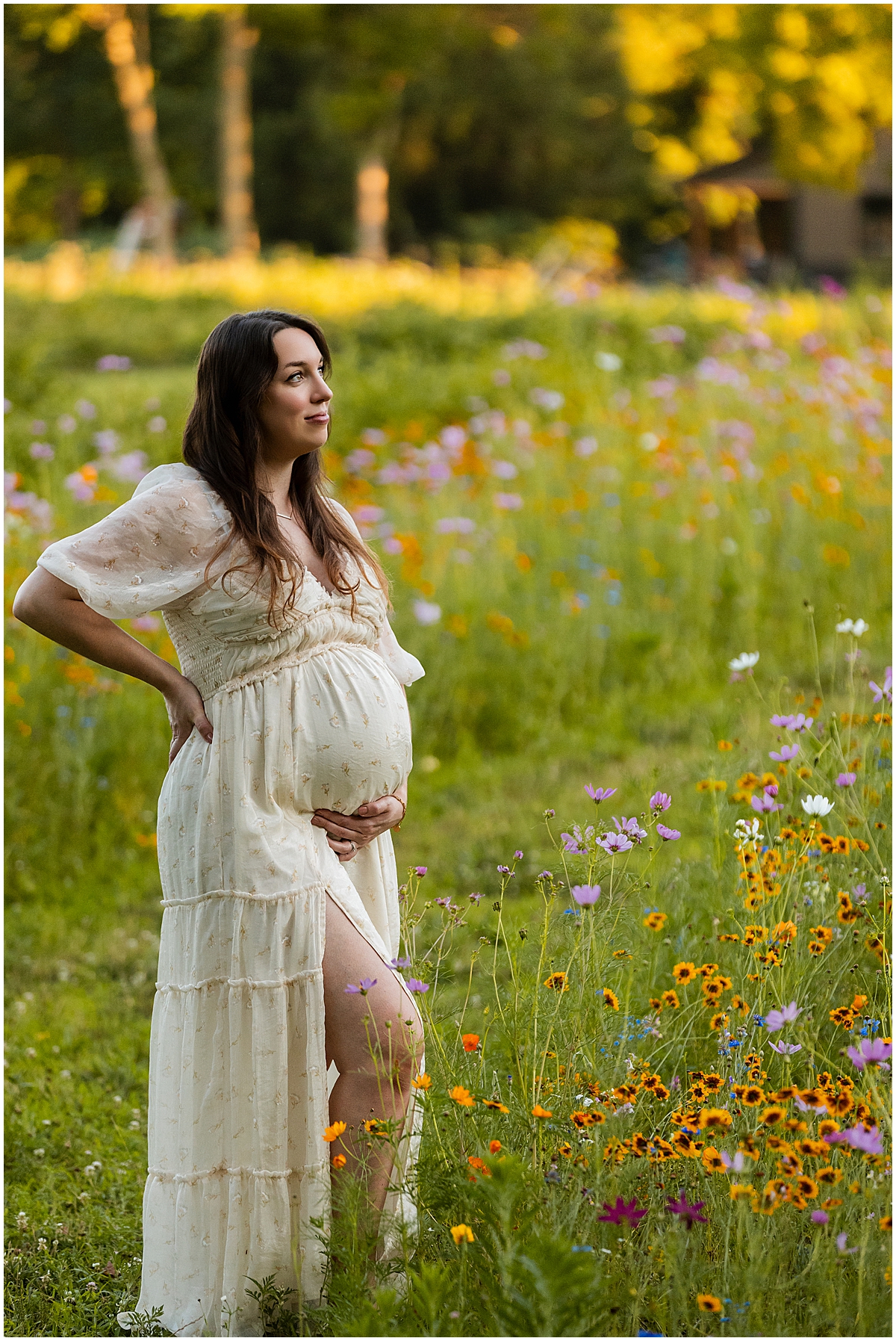 Pregnant mother in a cream dress standing beside colorful summer wildflowers