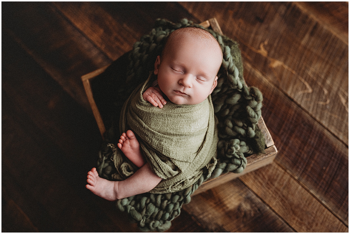 Newborn baby wrapped in olive green during an Indianapolis studio newborn session
