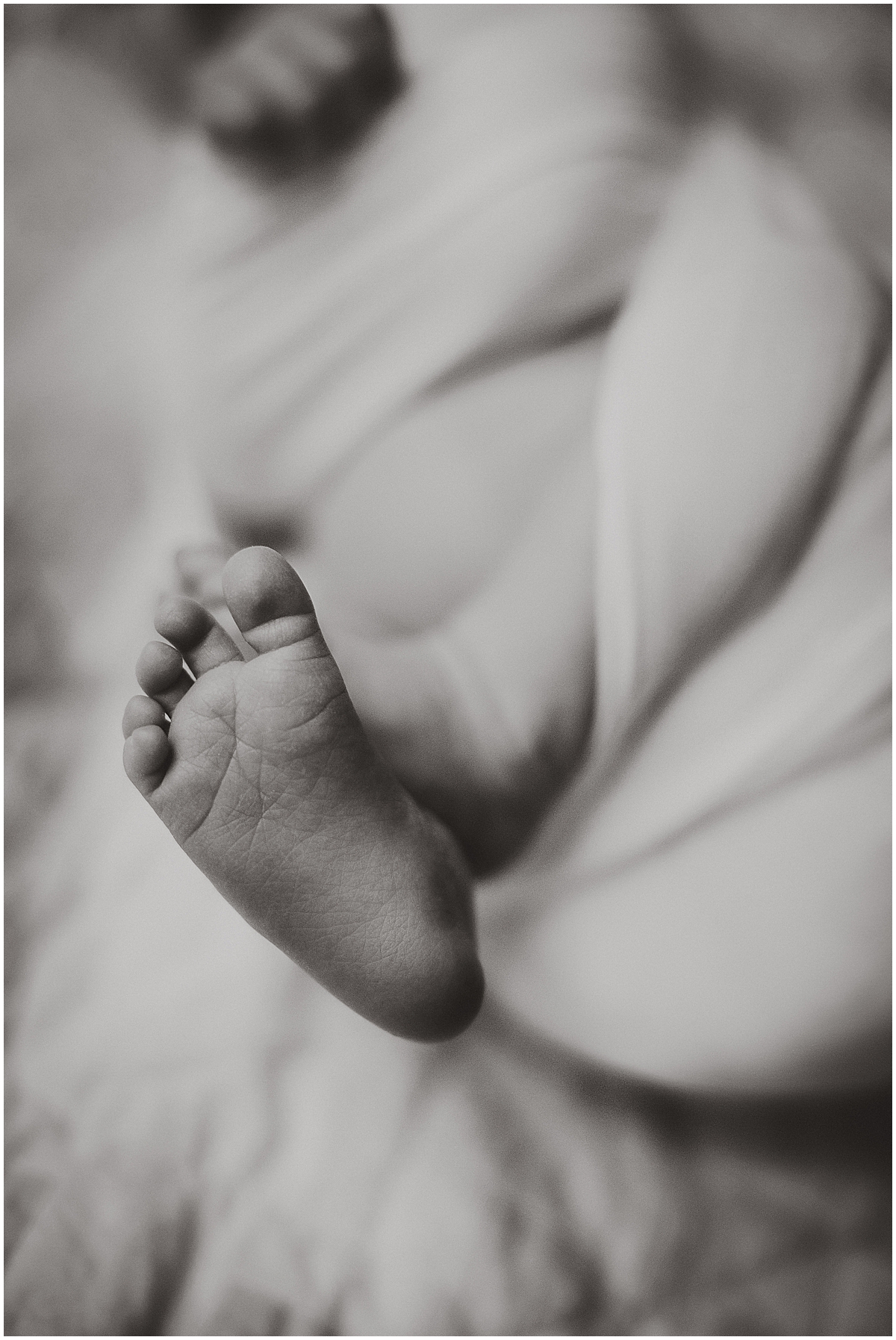 Black-and-white close-up of a newborn baby’s toes.