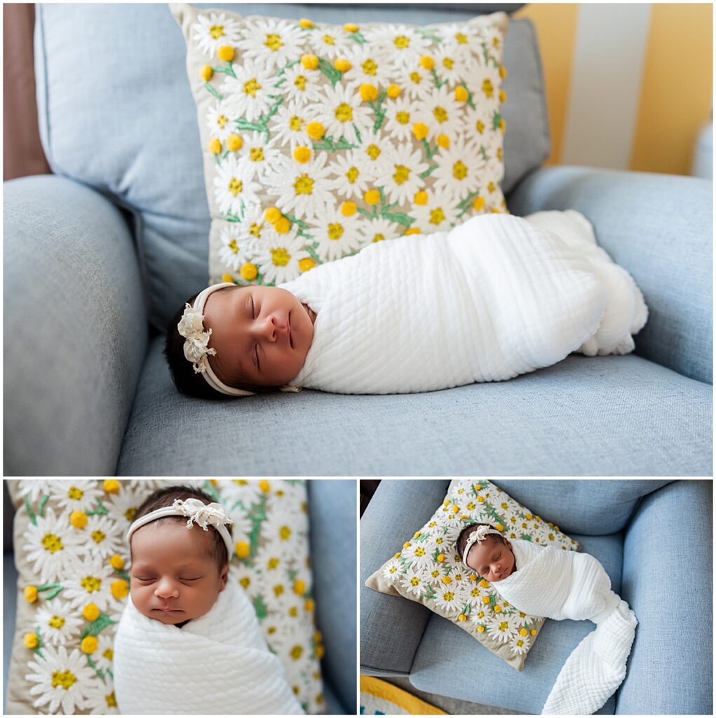 Newborn baby wrapped in white photographed on a blue nursery chair with a floral pillow.